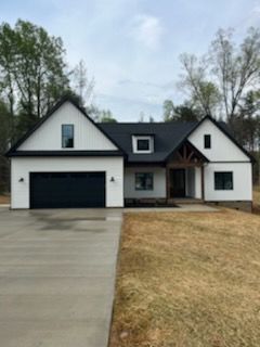 A white house with a black roof and a black garage door.