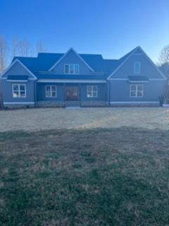 A large house with a blue roof is sitting in the middle of a grassy field.