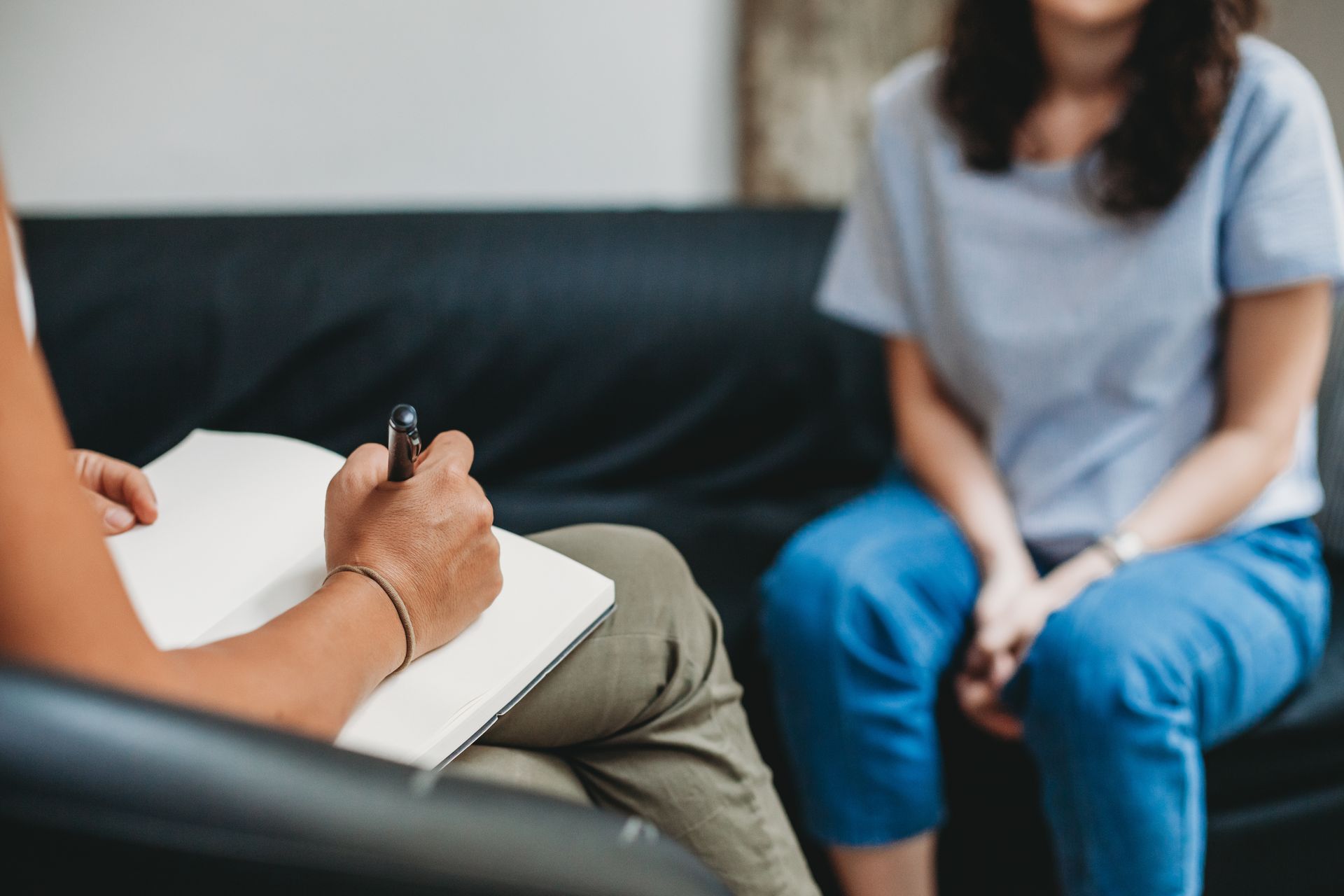 Therapist taking notes during a session with a client seated on a couch. Therapist taking notes during a session with a client seated on a couch.