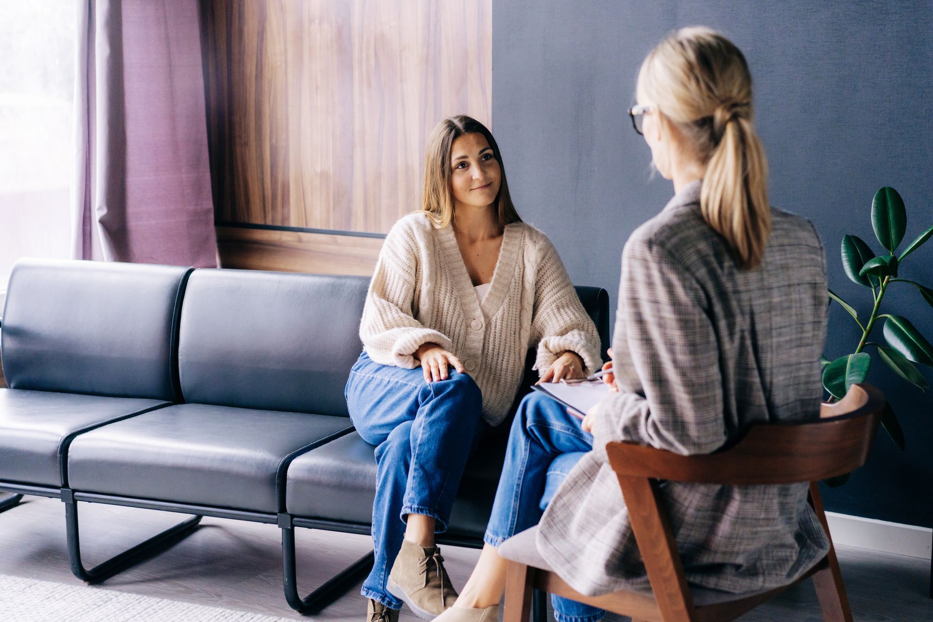 Woman on couch talking to person sitting in chair, inside a room. Woman on couch talking to person sitting in chair, inside a room.