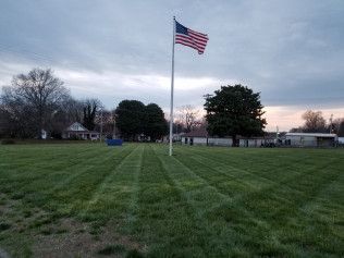 A large american flag is flying in a grassy field.