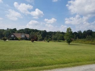 A large lush green field with a house in the background.