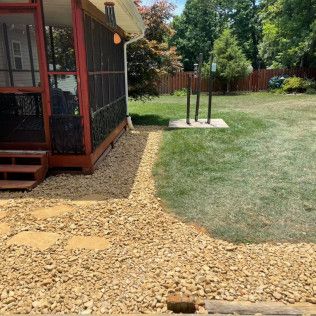 Backyard with a screened porch, gravel path, and grassy yard under trees.
