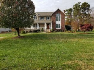 A large brick house with a large lawn in front of it.