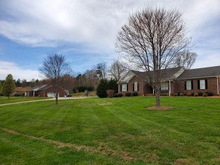 A large lush green lawn in front of a brick house.