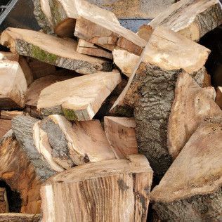 Stacked chopped firewood logs with rough bark and split pale wood faces