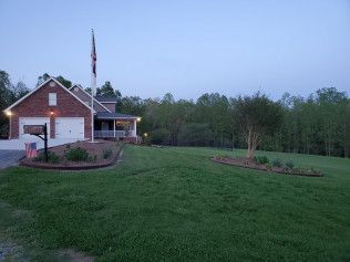 A brick house with a large lawn in front of it.