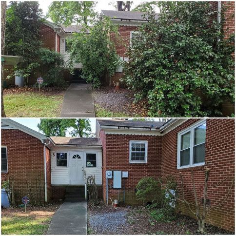 Brick house entrance overgrown with shrubs, showing front walkway and white double doors under a porch.