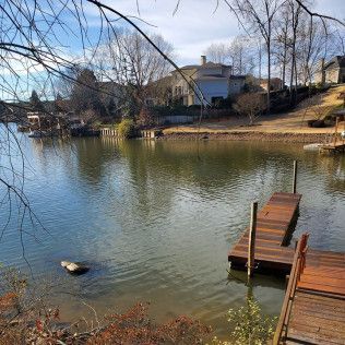 Quiet lakeside view with wooden dock, rippling water, and houses on the far shore