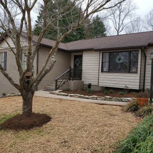 Suburban house with a leafless tree, front walkway, and landscaped yard in winter