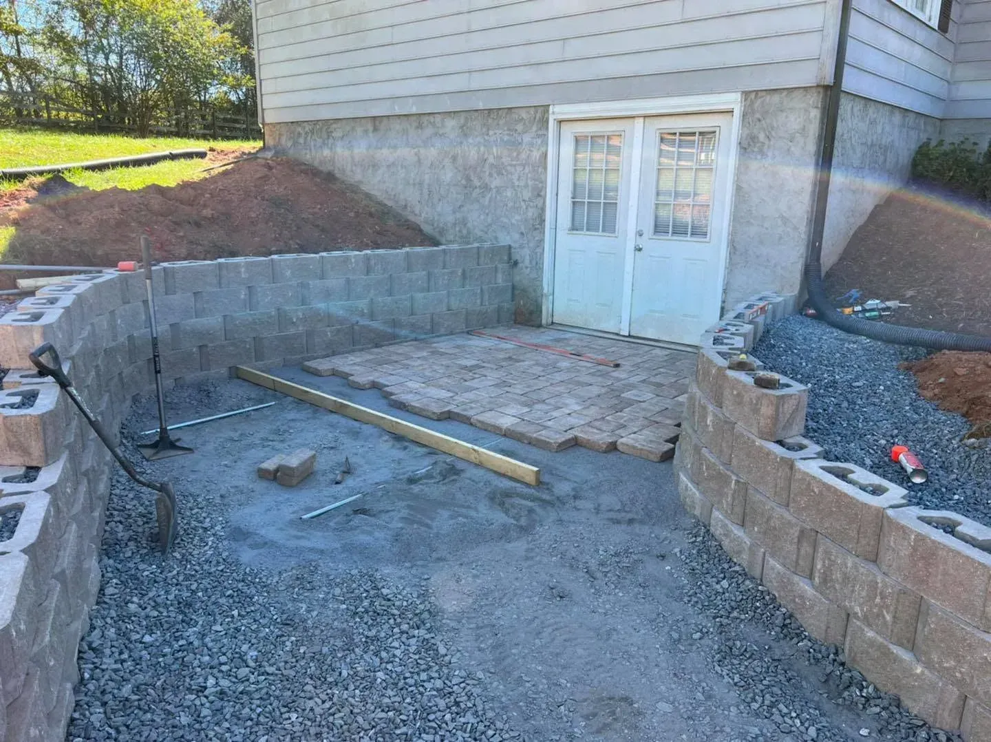 Paver patio installation in progress with retaining walls and a compacted gravel base in Conover, NC
