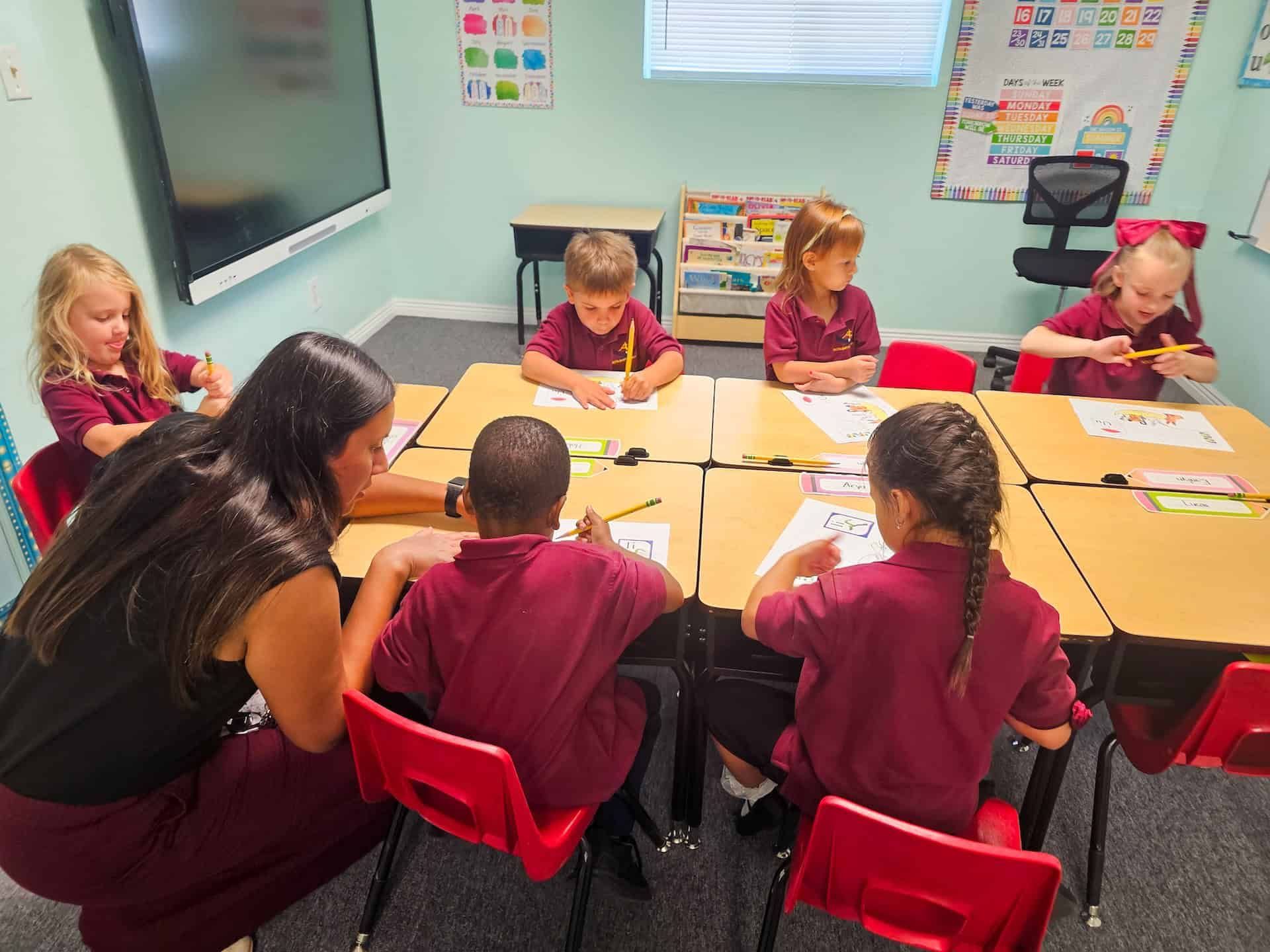 Children coloring at a table in a classroom or art activity, with crayons and paper.