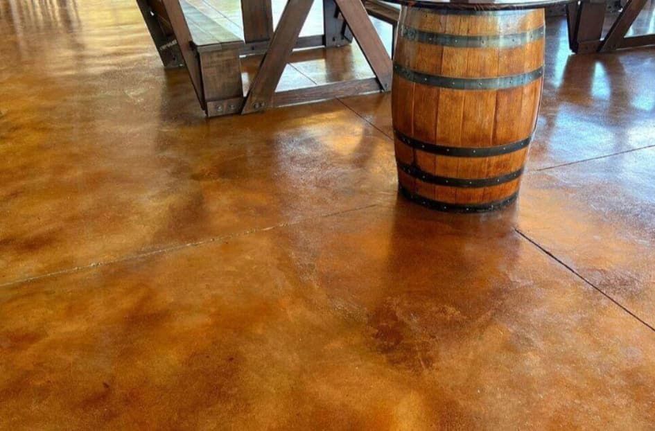 A wooden barrel is sitting on a concrete floor next to a table.