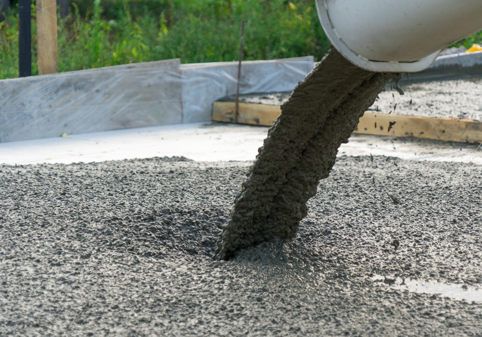 A person is pouring concrete into a hole in the ground