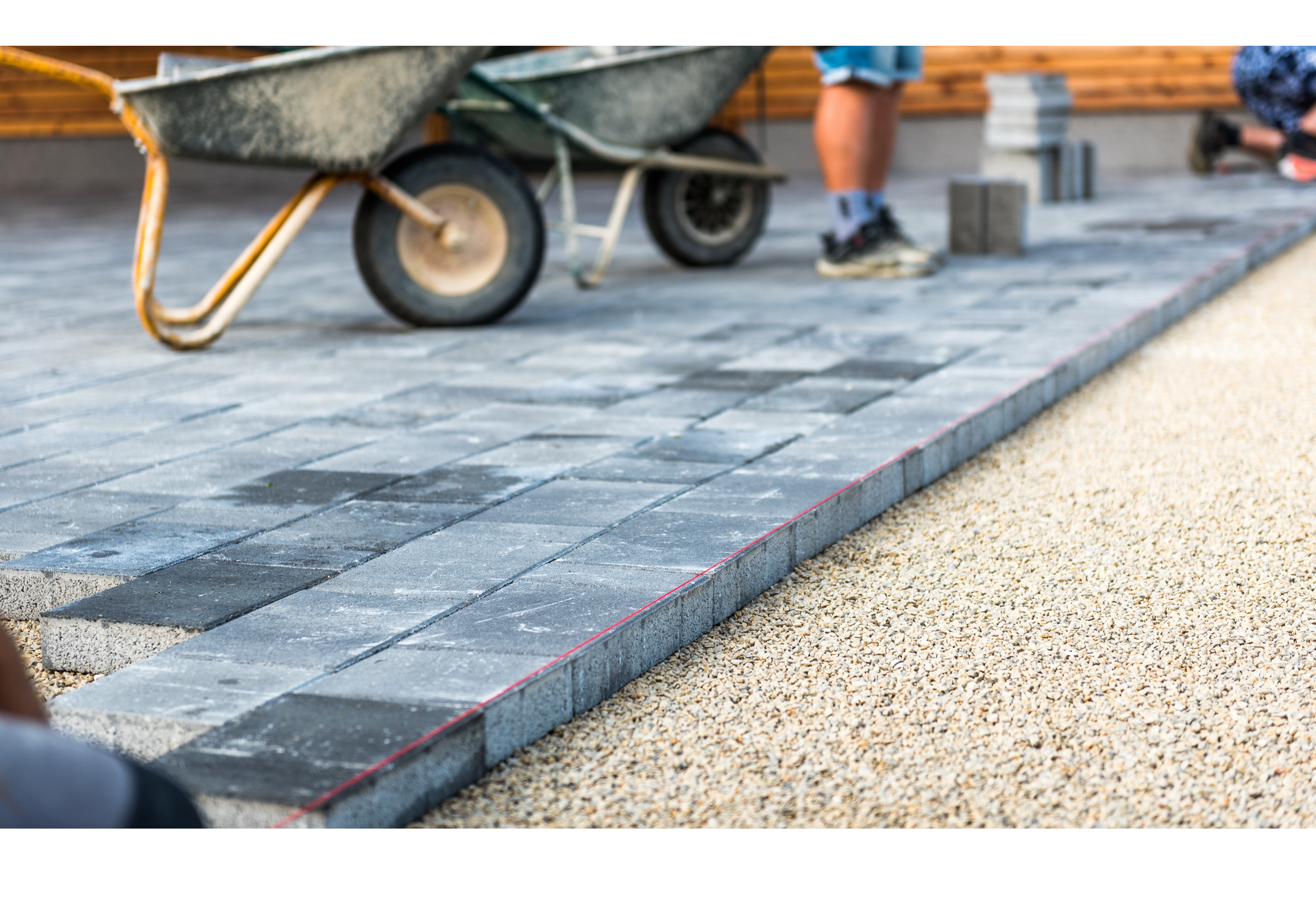 A person is pushing a wheelbarrow on a brick walkway.
