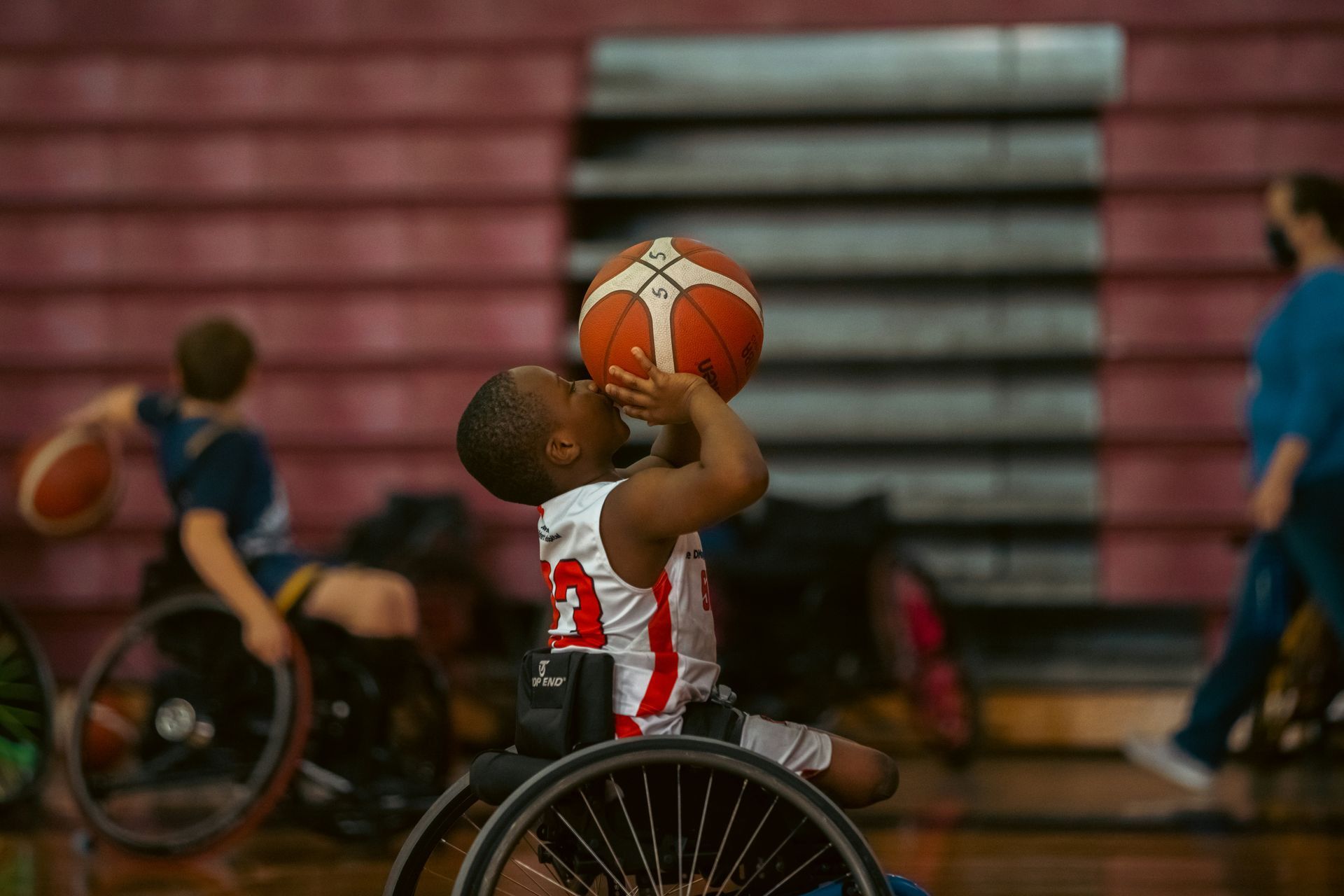 A young boy in a wheelchair shooting a basketball