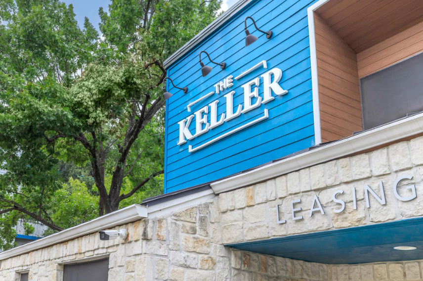 Blue sign reading “The Keller” above a stone building exterior and awning.