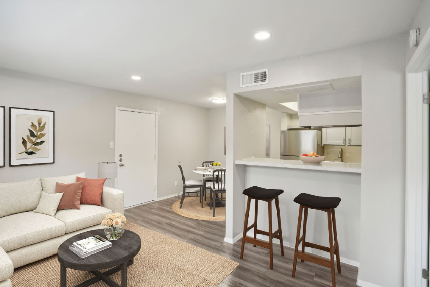 Bright modern living room with sofa, coffee table, bar stools, and open kitchen pass-through