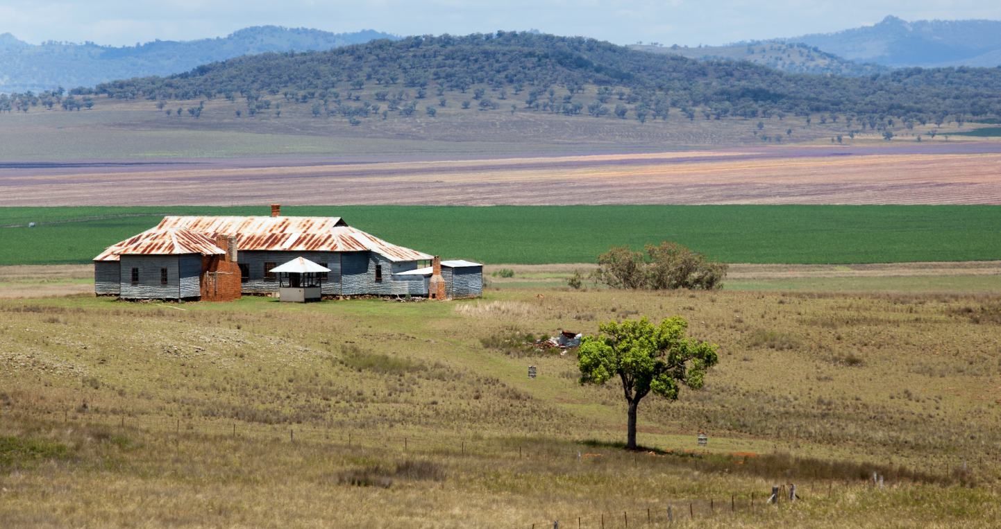 A House In The Middle Of A Field With Mountains In The Background — Caterpillar Tree Services In Armidale, NSW