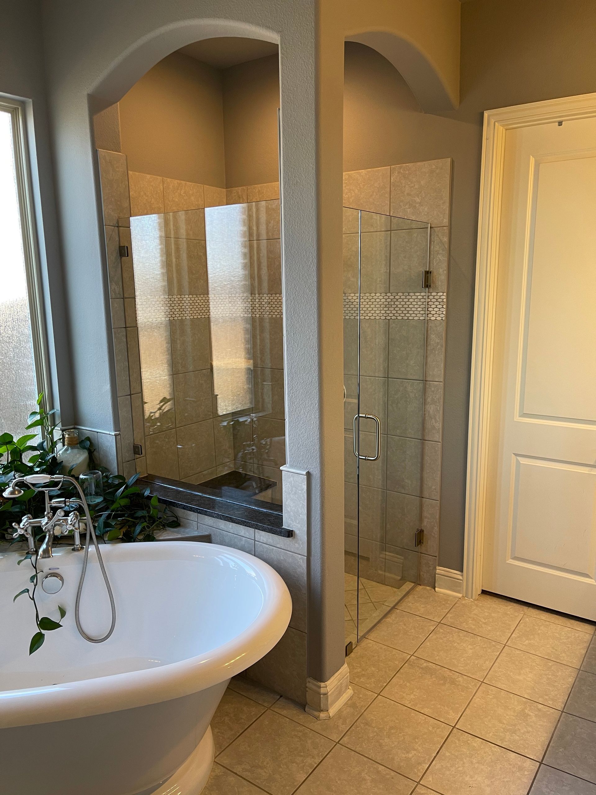 Bathroom with a freestanding tub, glass shower, and white door.