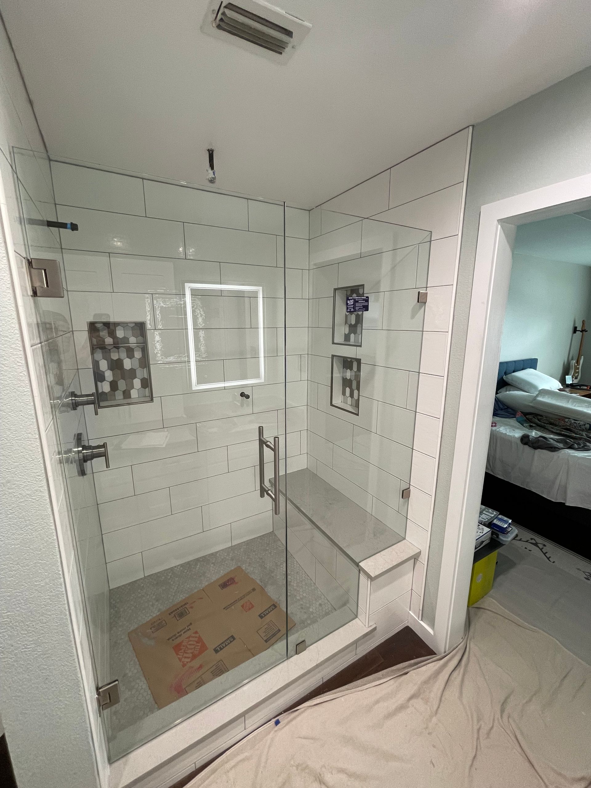 Glass shower with white tile walls and a built-in bench.