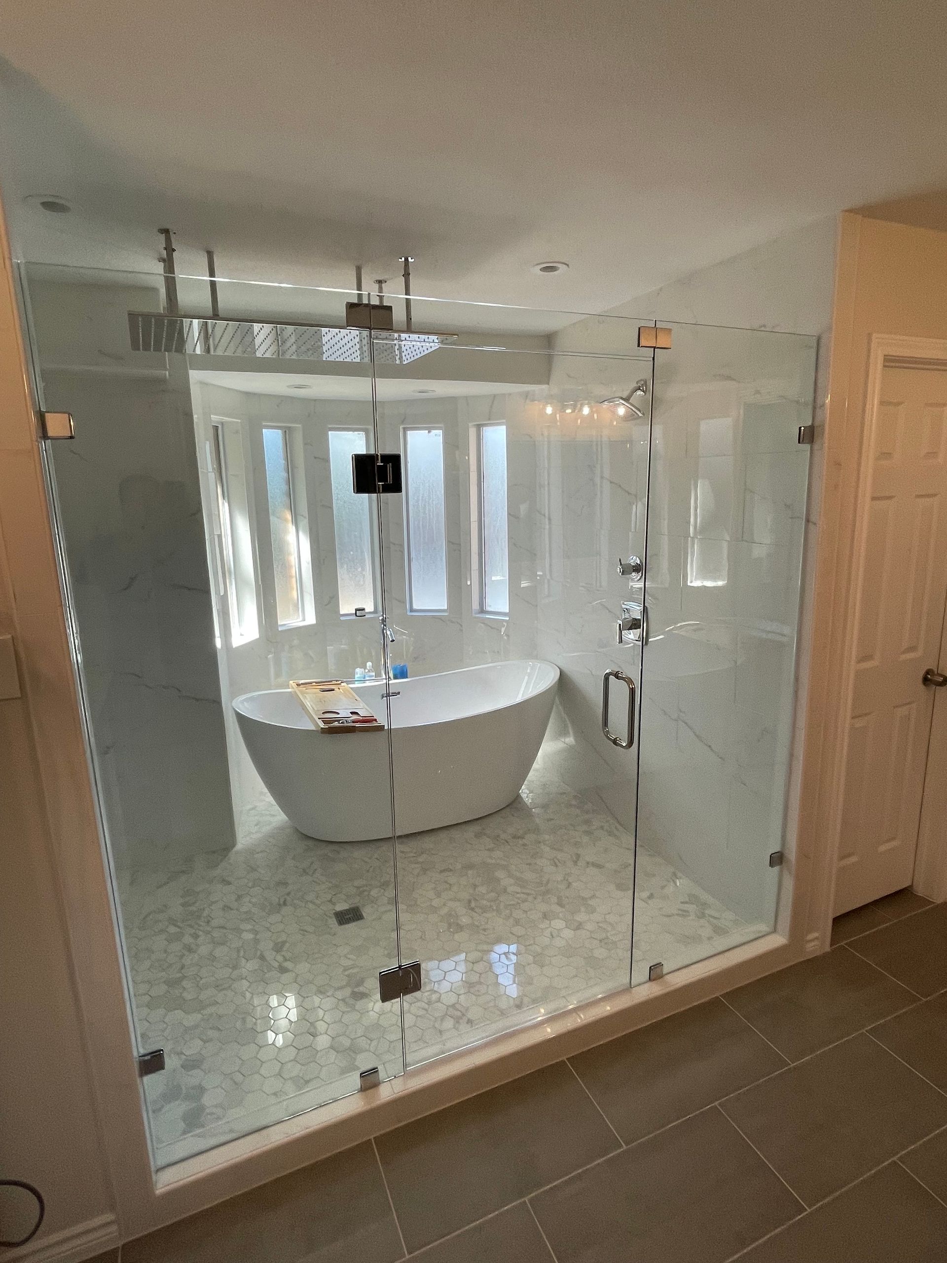 Modern bathroom with a glass-enclosed shower, freestanding tub, and window with frosted glass.