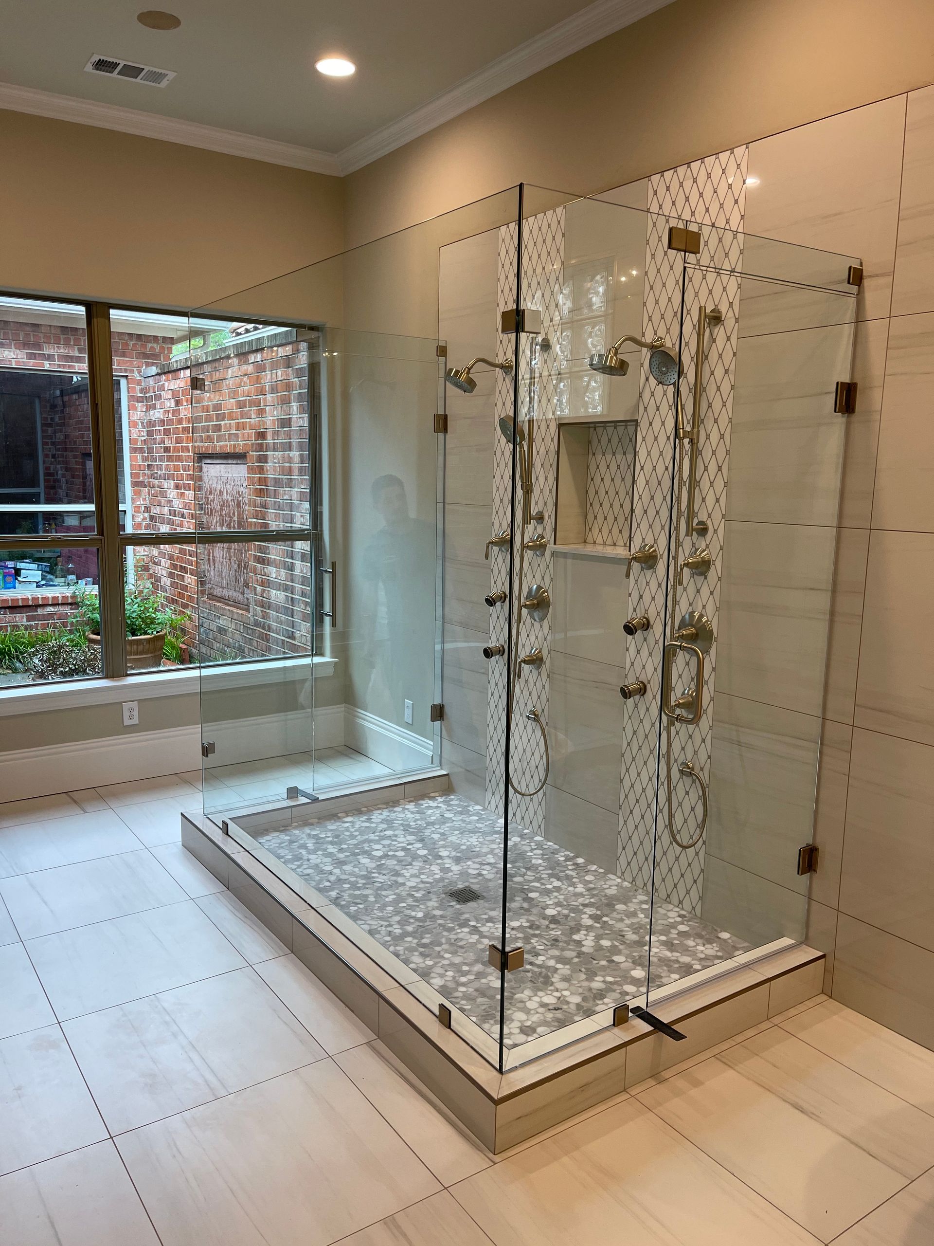 Luxurious modern shower with glass doors, multiple showerheads, and tiled walls and floor.