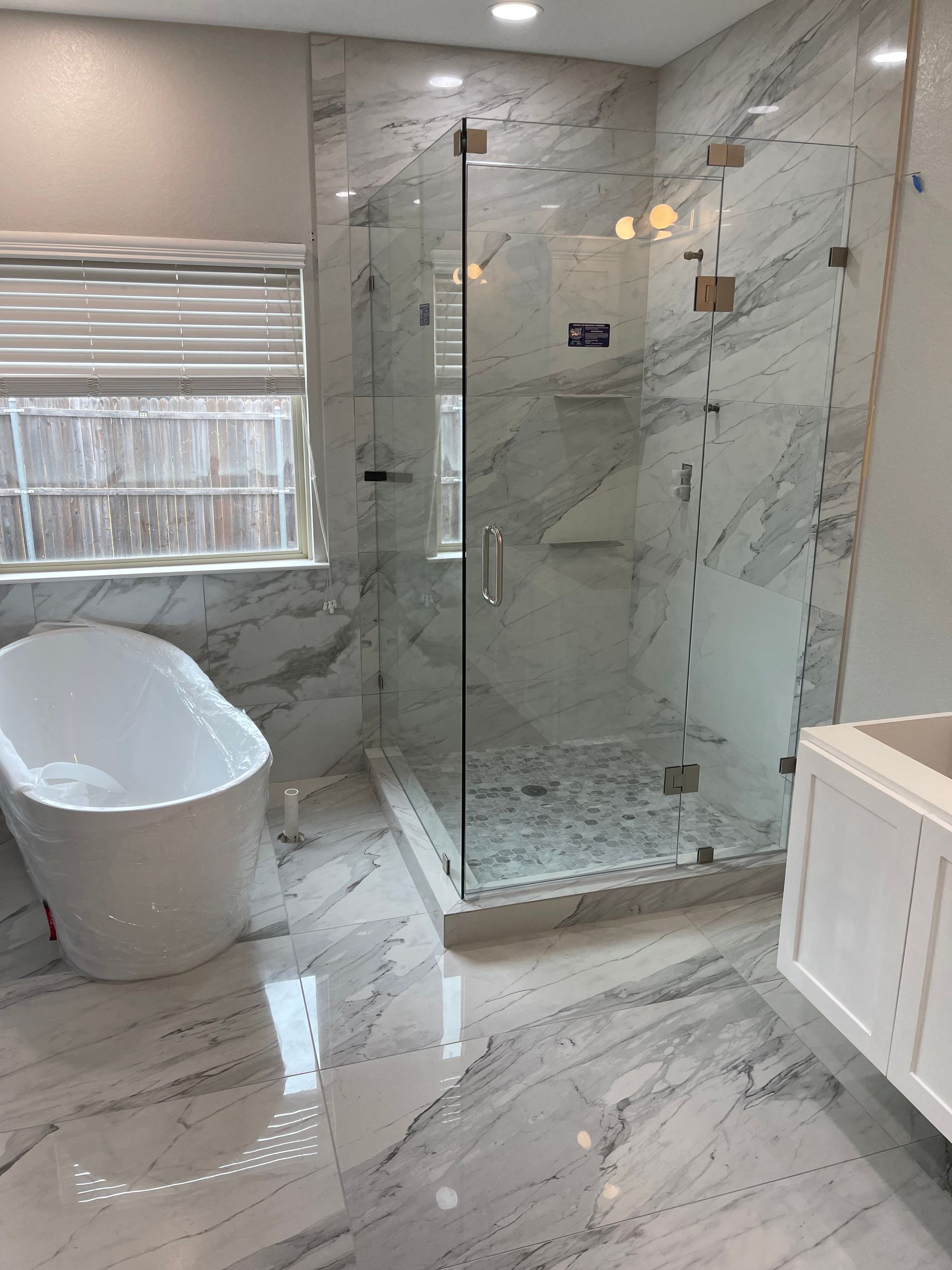 Luxury bathroom with a glass shower, soaking tub, and marble tile.