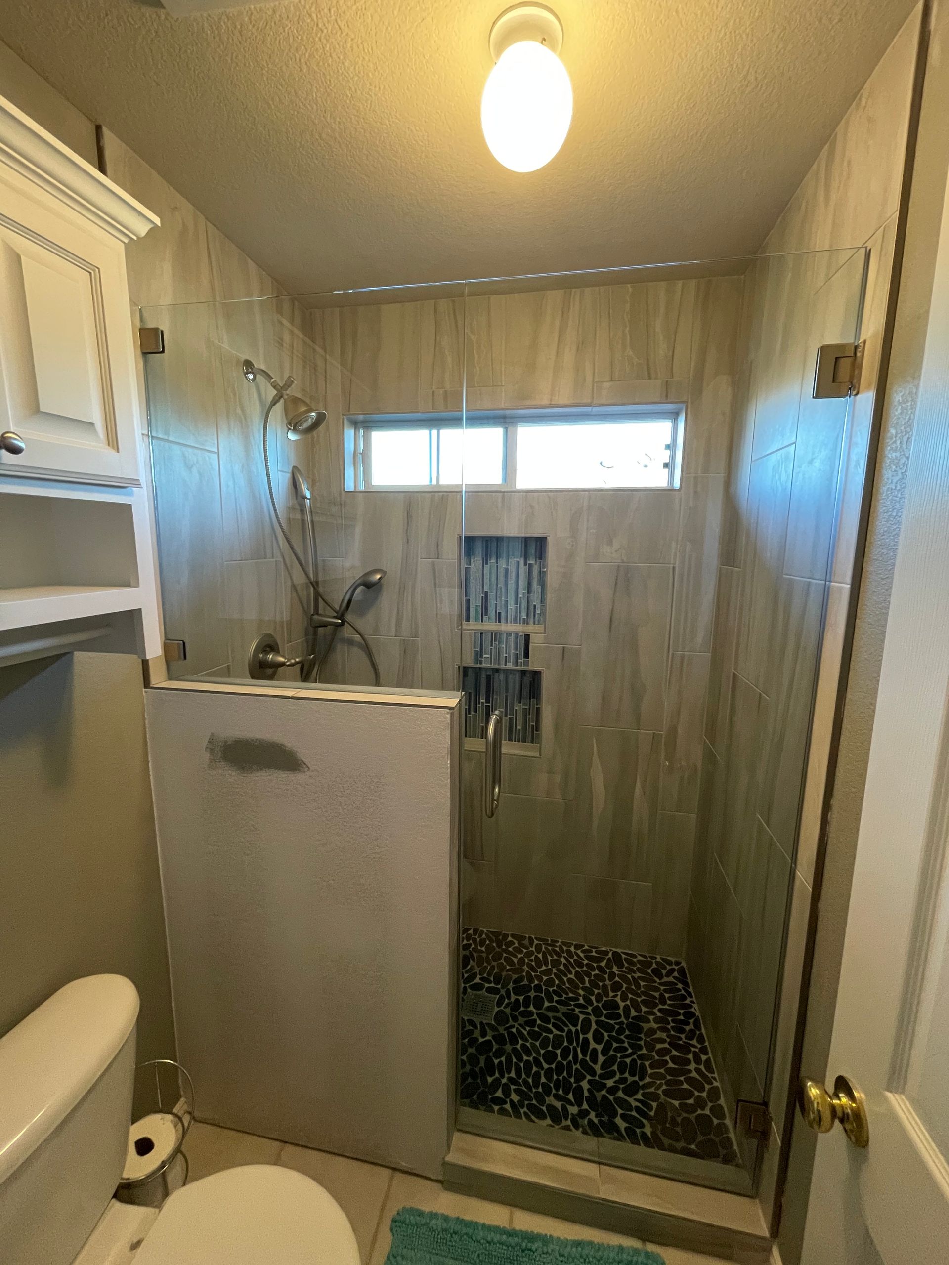 Bathroom with a tiled shower stall and a toilet.