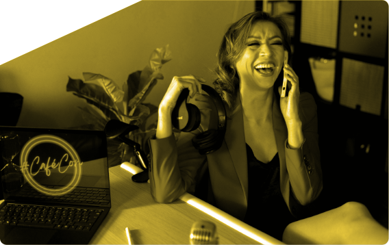 A woman laughs while talking on a cell phone in front of a cafe c logo