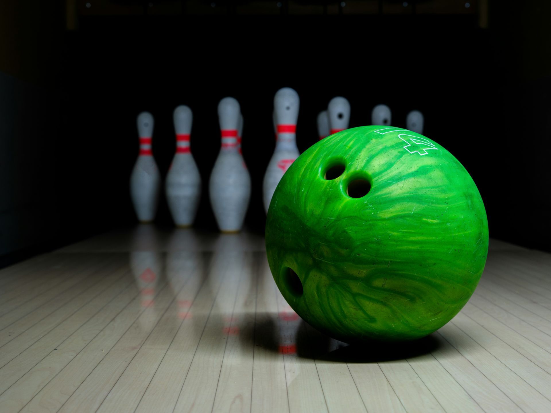 A green bowling ball is sitting on a bowling alley