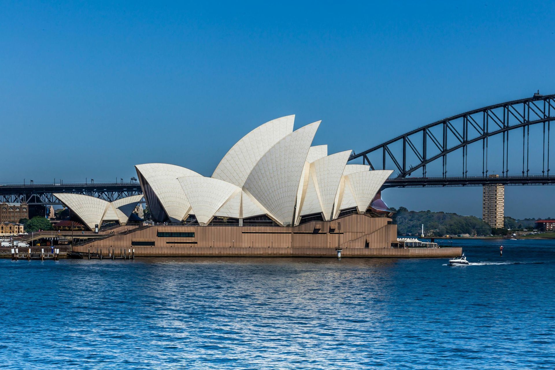 The sydney opera house sits in the middle of a body of water