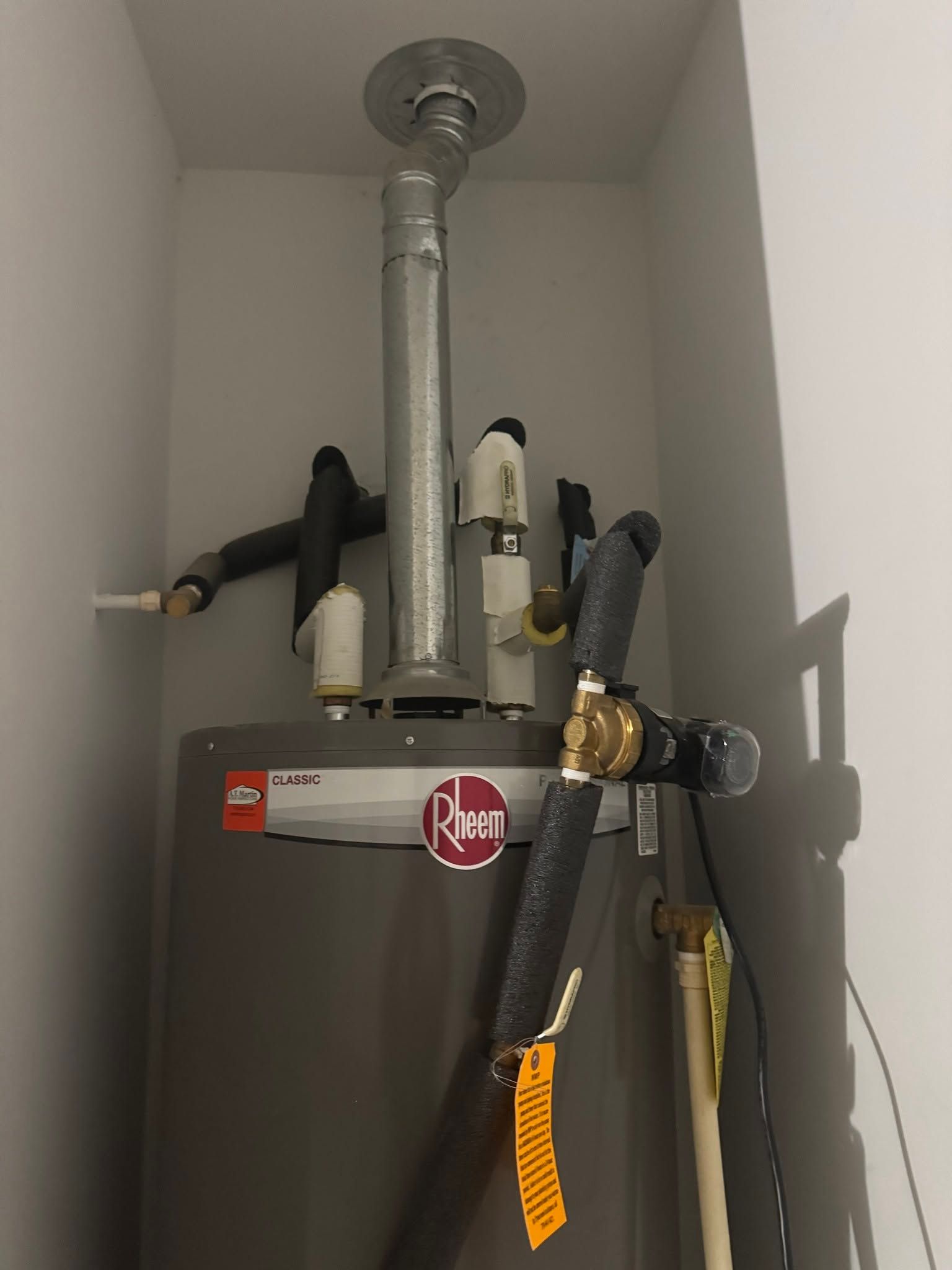 Water heater with pipes and shutoff valves in a small utility closet