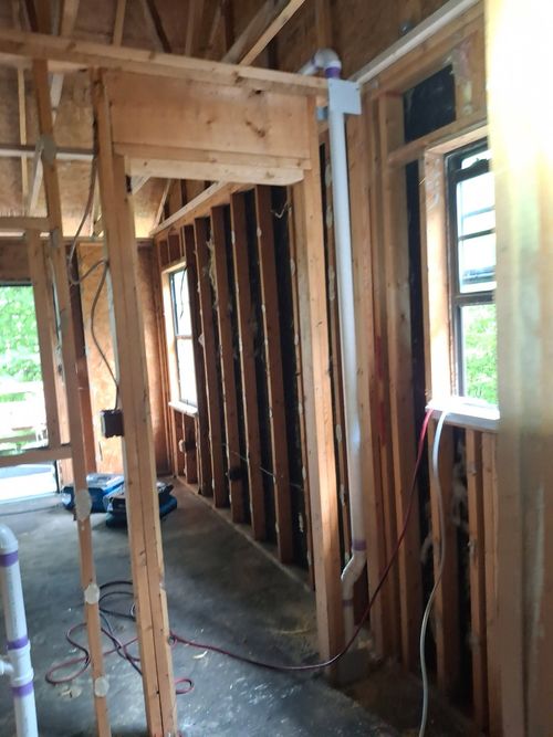 Interior of a house under construction with exposed wooden framing and open window spaces.