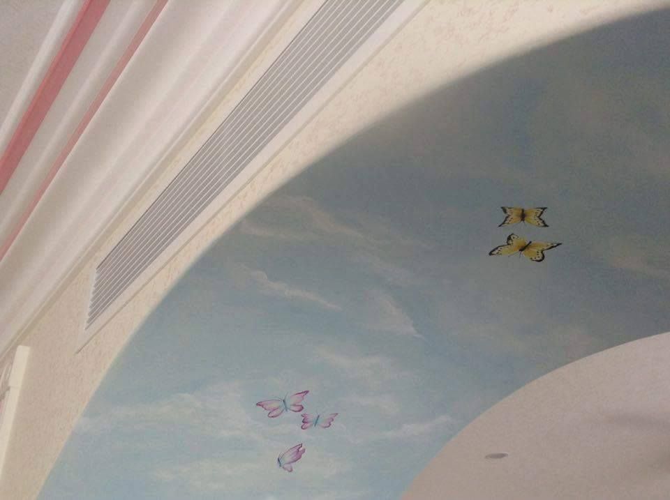 A ceiling with a painting of butterflies and clouds on it