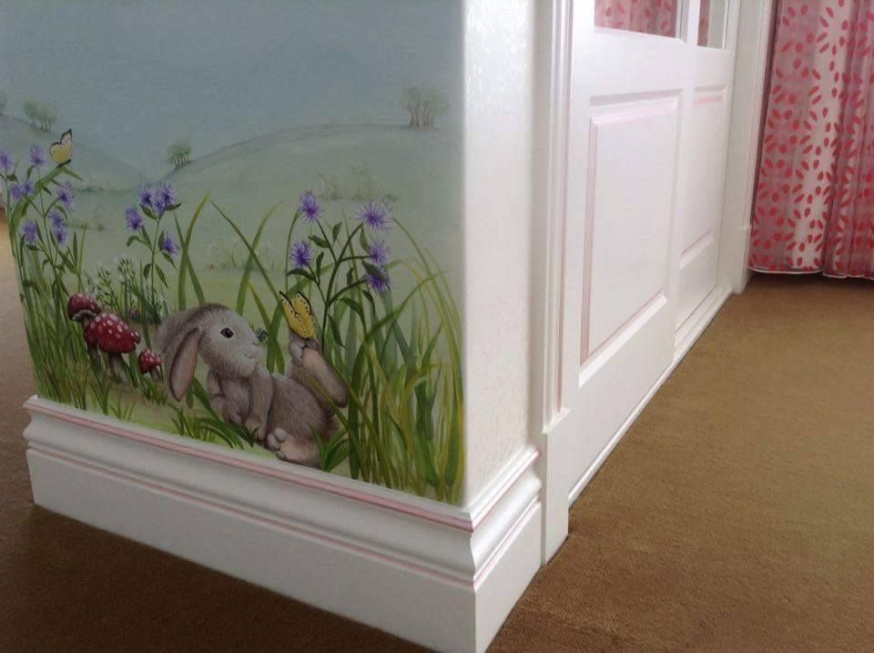 A corner of a room with a painting of a rabbit in the grass.