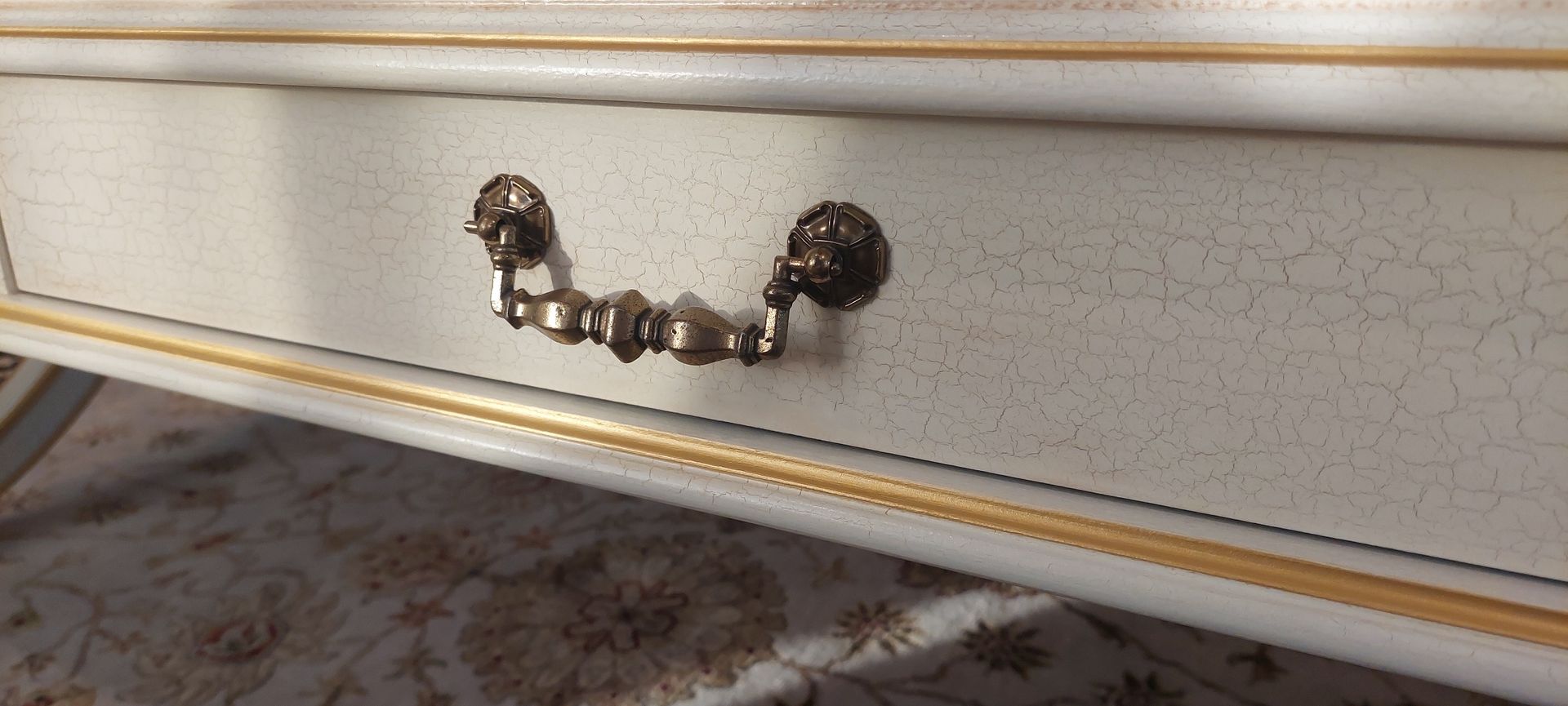 A close up of a white and gold drawer on a table.
