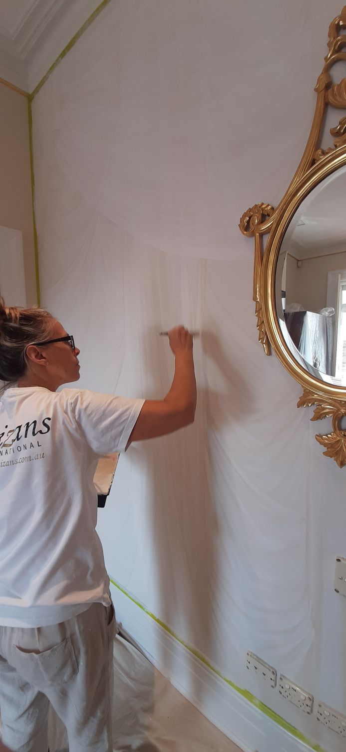 A man is painting a wall next to a mirror.