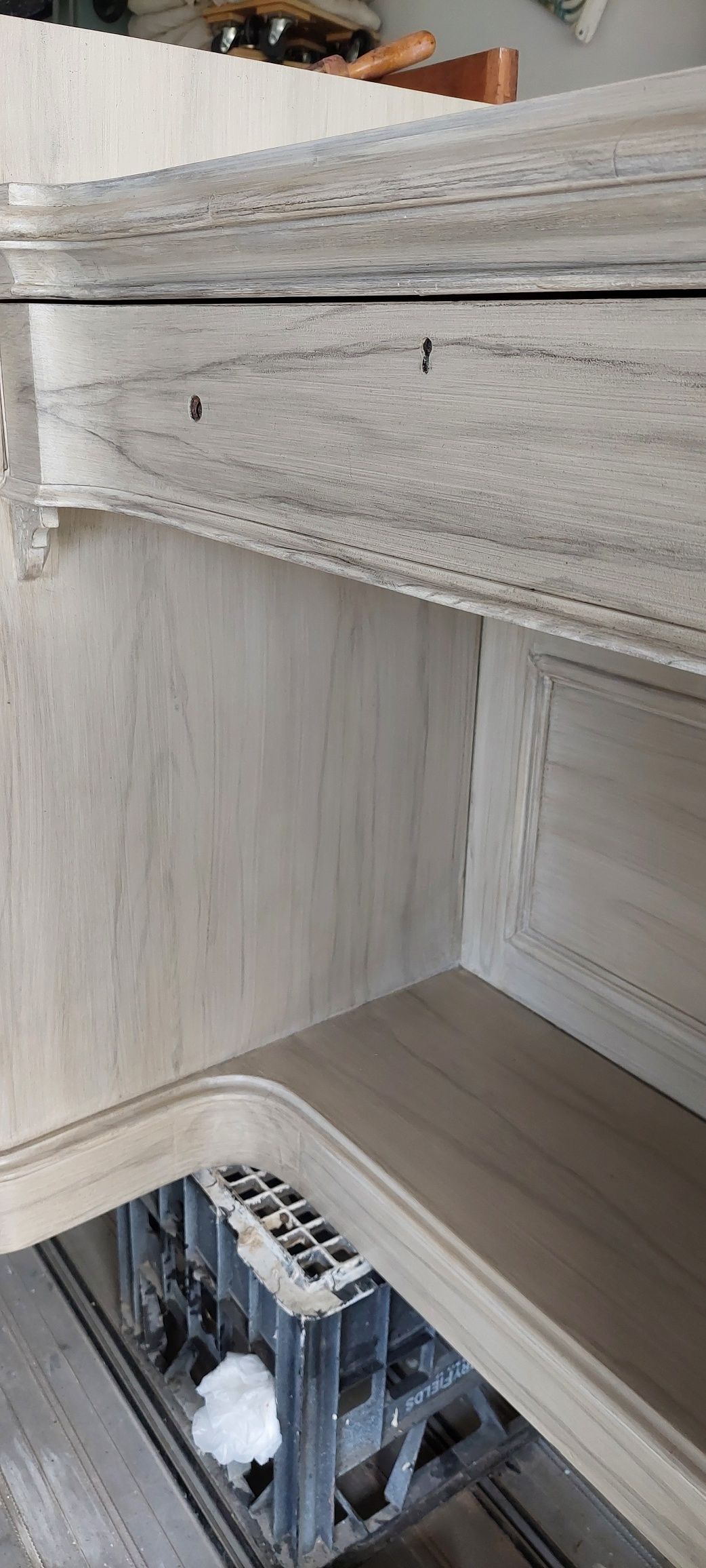 A close up of a white wooden cabinet with a shelf.