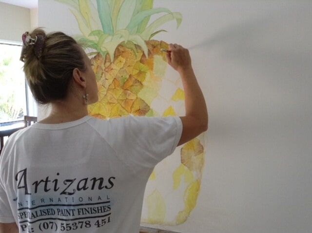 Woman Paints A Pineapple On A Canvas — Artizans International Specialised Paint Finishes in Robina, QLD