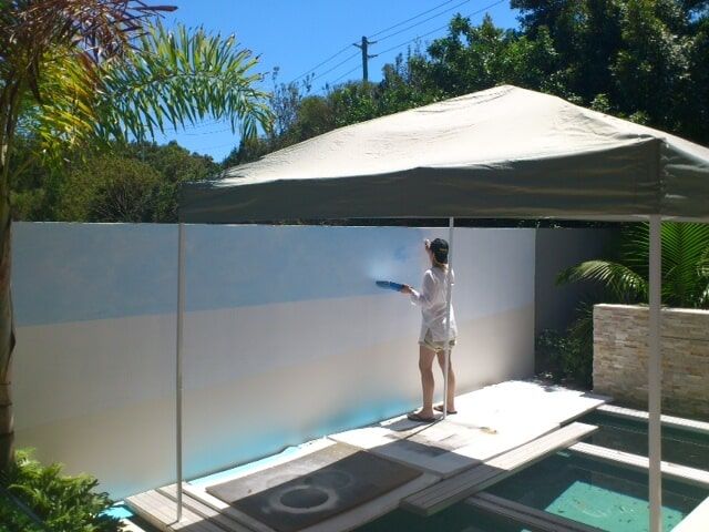 Woman Paints On A Wall Beside The Pool — Artizans International Specialised Paint Finishes in Robina, QLD