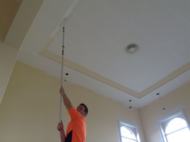 Man Paints The Ceiling With White Paint — Artizans International Specialised Paint Finishes in Robina, QLD