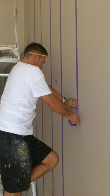 Man Adding A Tape Mark On The Wall — Artizans International Specialised Paint Finishes in Robina, QLD