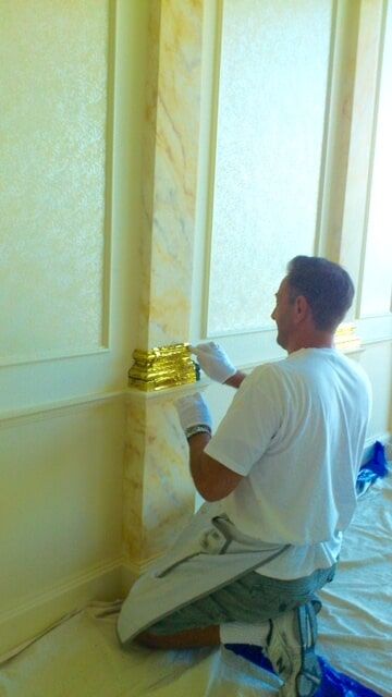 Man Adding A 24 Karat Gold Leaf Gliding On A Post — Artizans International Specialised Paint Finishes in Robina, QLD