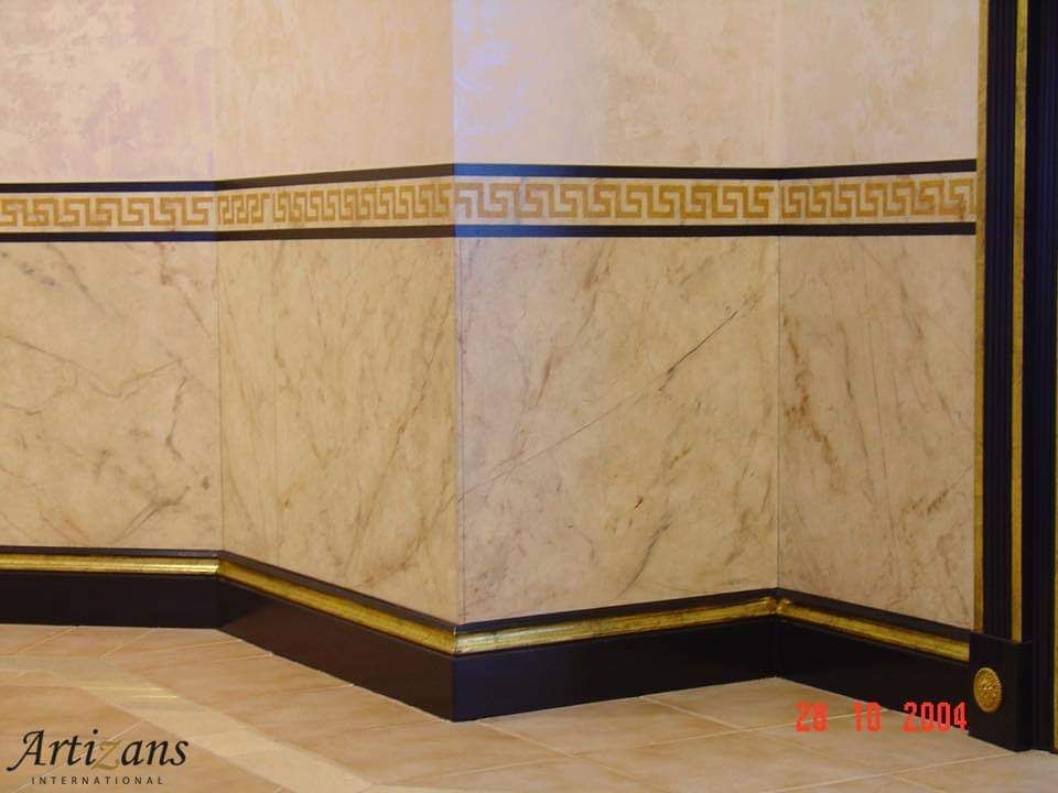 A corner of a room with a greek key design on the wall