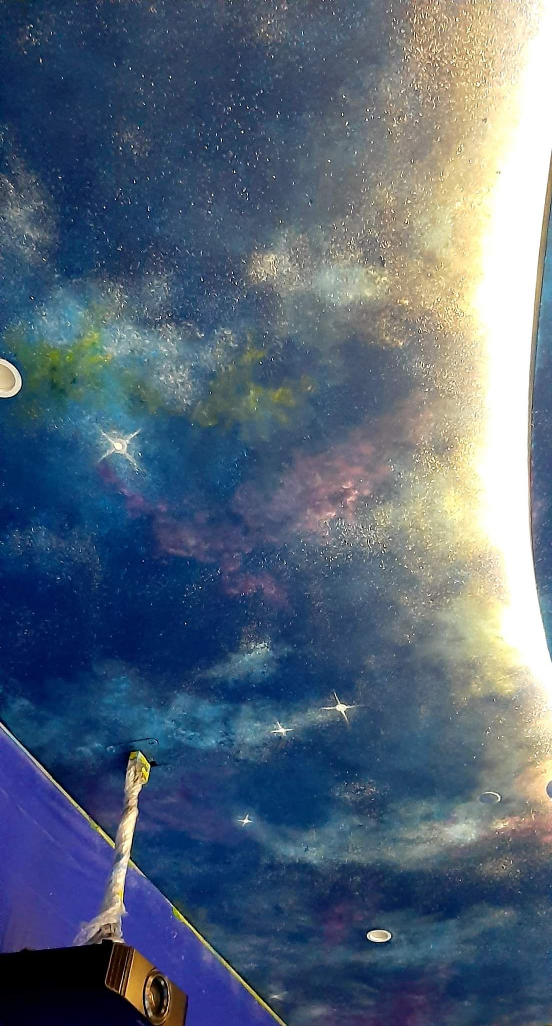 A painting of a galaxy on the ceiling of a room.