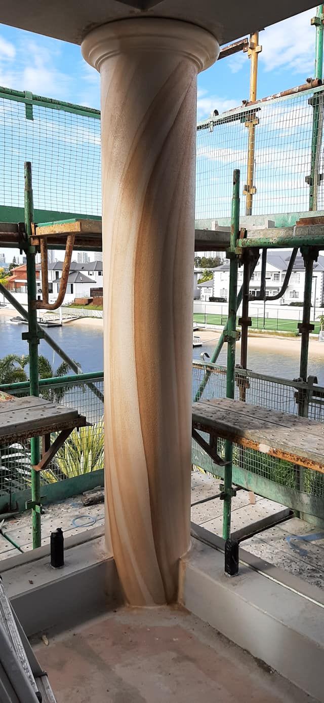 A pillar is being built on top of a building with scaffolding around it.