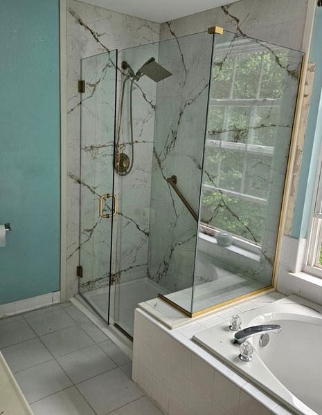 Frameless corner shower enclosure with brushed brass hardware and marble tile