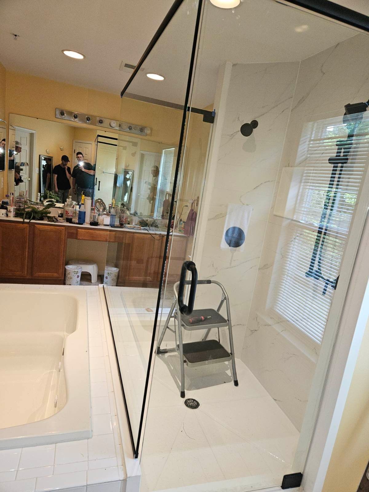 Frameless corner enclosure with matte black hardware over a tub deck in Baltimore, MD