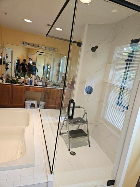 Frameless corner shower enclosure with matte black hardware and a tub deck